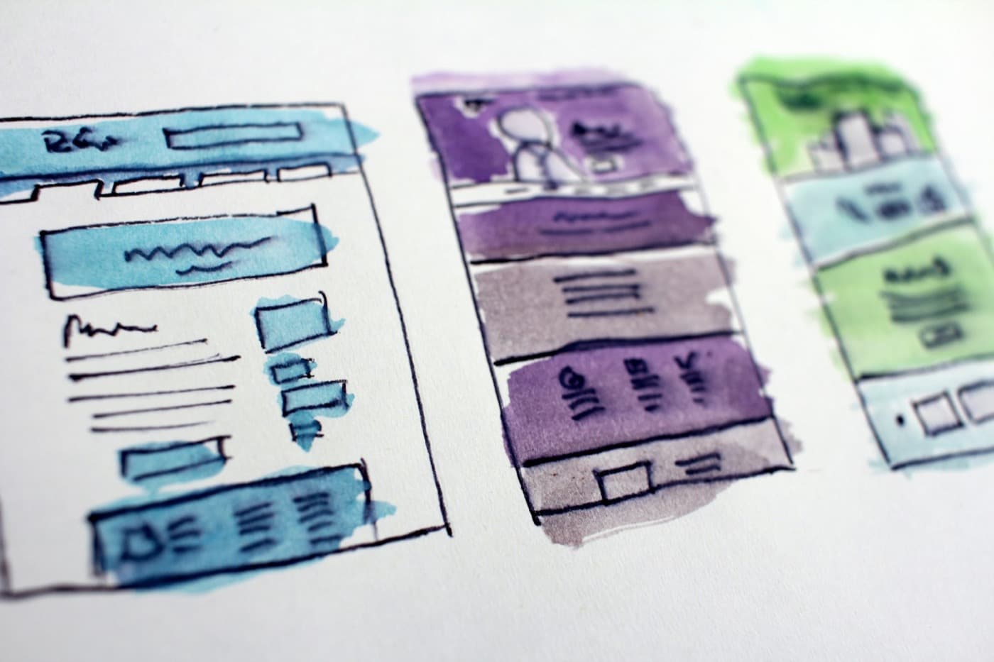 Watercolour wireframe sketches of web page layouts on paper